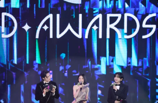 Performers on the D Awards stage in front of a large illuminated D AWARDS backdrop